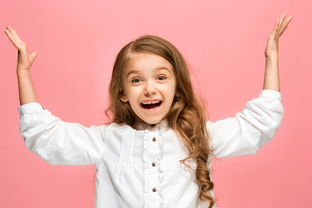 The happy teen girl standing and smiling against pink background.の写真素材