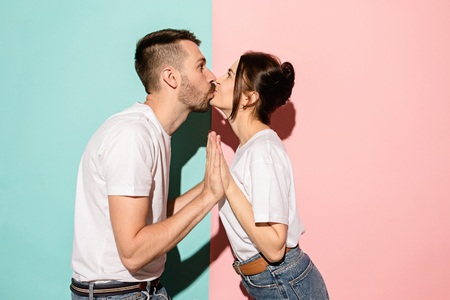 A view of a loving couple kissing on blue and pink backgroundの写真素材
