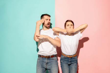 Closeup portrait of young couple, man, woman. TV fan concept on pink and blue background. Emotion...