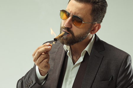 The barded man in a suit holding cigarの写真素材