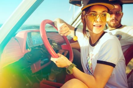 Laughing romantic couple sitting in car while out on a road trip at summer dayの写真素材