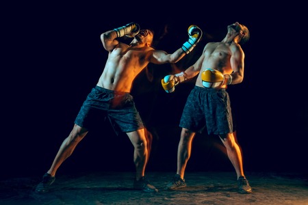 Male boxer boxing in a dark studioの写真素材
