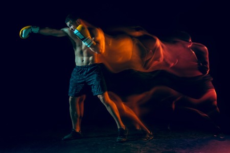 Male boxer boxing in a dark studioの写真素材