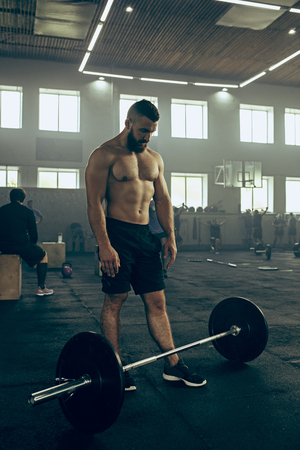 Fit young man lifting barbells working out in a gymの写真素材