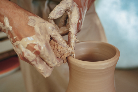 Creating a jar or vase of white clay close-up. Master crock. Man hands making clay jug macro.の写真素材