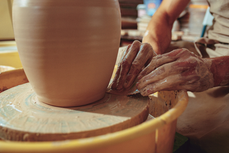 Creating a jar or vase of white clay close-up. Master crock. Man hands making clay jug macro.の写真素材