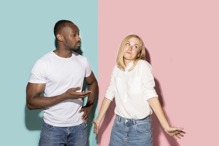 Beautiful female and male portrait on pink and blue studio backgroud. The young emotional couple
