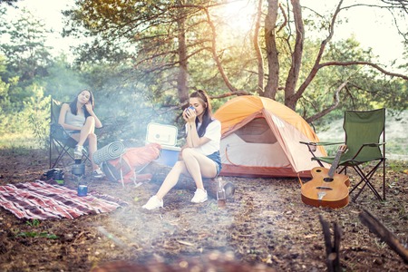 Party, camping of women at forest. They relaxing, singing a song and cooking barbecueの写真素材