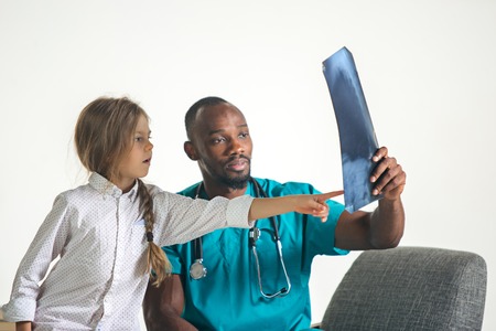 Young afro male pediatrician explaining X-ray to child at clinic. The doctor, health, medicine,...