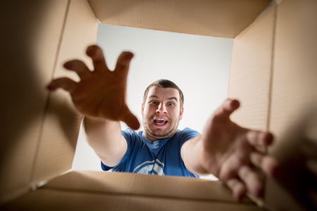 The surprised man unpacking, opening carton box and looking inside. The package, delivery, surprise,...