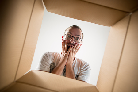 The surprised man unpacking, opening carton box and looking inside. The package, delivery, surprise,...
