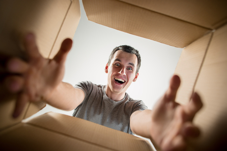 The surprised man unpacking, opening carton box and looking inside. The package, delivery, surprise,...