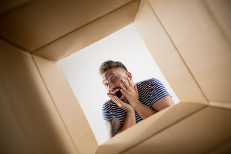 The surprised man unpacking, opening carton box and looking inside. The package, delivery, surprise,...