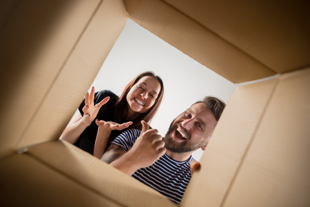 The surprised man and woman unpacking, opening carton box and looking inside. The package, delivery, surprise, gift lifestyle conceptの写真素材