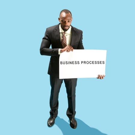 The afro businessman holding a white poster with word business processes. Business, choice of...