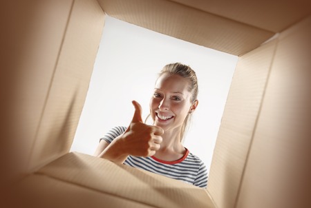 The surprised woman unpacking, opening carton box and looking inside. The package, delivery,...