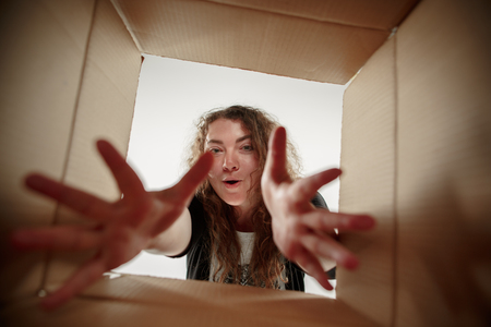 The surprised woman opening box and looking inside. The package, delivery, surprise, gift, lifestyle concept. Human emotions conceptsの写真素材