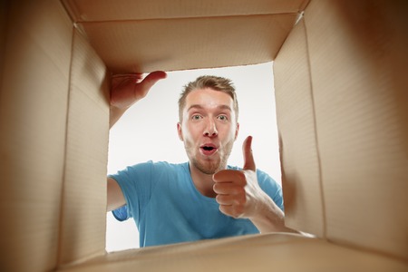 Man smiling, opening box and looking inside. The package, delivery, surprise, gift and lifestyle conceptの写真素材