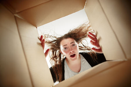 The surprised woman opening box and looking inside. The package, delivery, surprise, gift, lifestyle concept. Human emotions conceptsの写真素材