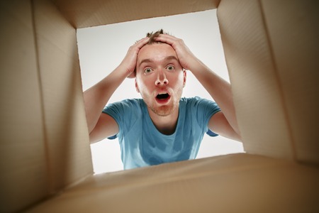 Man smiling, opening box and looking inside. The package, delivery, surprise, gift and lifestyle conceptの写真素材