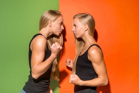 Angry women. Aggressive women standing isolated on trendy studio background. Female half-length portrait. Human emotions, facial expression concept. Front view.の写真素材