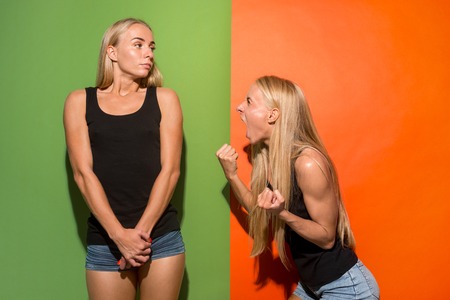 Angry woman. Aggressive woman standing isolated on trendy studio background. Female half-length portrait. Human emotions, facial expression concept. Front view.の写真素材