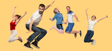 Freedom in moving. Mid-air shot of pretty happy young man and women jumping and gesturing against...