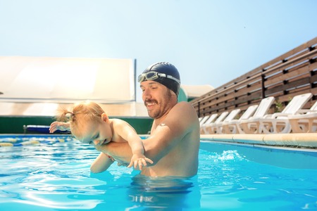 Happy family having fun by the swimming pool. Pool, leisure, swimming, summer, recreation, healthy lifstyle conceptの写真素材