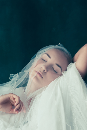 Beautiful bride looking over her veil as she hold it up in front of her faceの写真素材