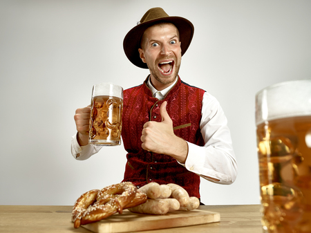 Germany, Bavaria, Upper Bavaria. The young happy smiling man with beer dressed in traditional...