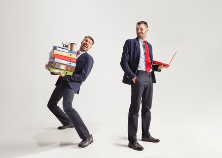 Young businessman in a suit juggling with office supplies in his office, isolated on white background. Conceptual collage with phone, folders. The business, office, work concept.の写真素材