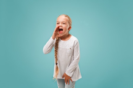 Do not miss. Young casual teen girl shouting. Shout. Crying emotional teenager screaming on blue...