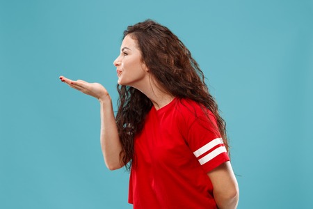 Happy business woman standing and kissing isolated on blue studio background. Beautiful female...