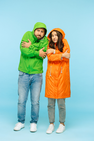 The young couple posing at studio in autumn jacket isolated on blue.の写真素材