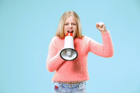 Teen girl making announcement with megaphone at blue studioの写真素材