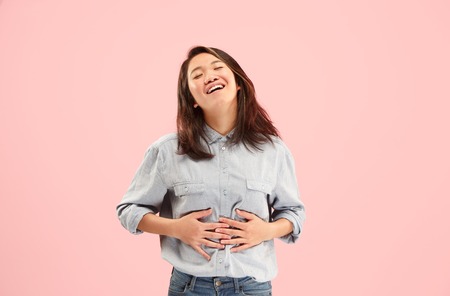 Delight. Beautiful female half-length front portrait isolated on pink studio backgroud. Young, emotional, smiling, surprised woman standing. Human emotions, facial expression concept. Trendy colorsの写真素材
