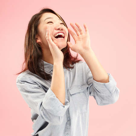 Do not miss. Young casual woman shouting. Shout. Crying emotional woman screaming on studio background. Female half-length portrait. Human emotions, facial expression concept. Trendy colorsの写真素材