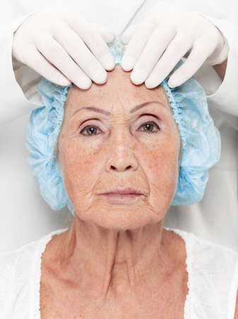 The surgeon doing skin check on mid age woman before plastic surgery. Senior female model. plastic surgery, lifting, aging conceptの写真素材
