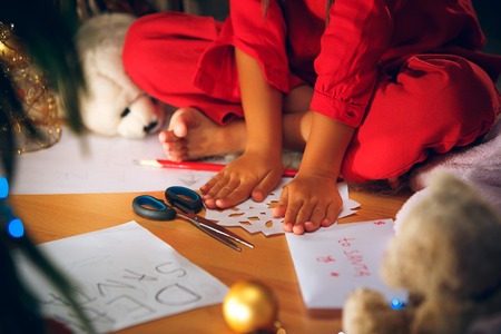 Beautiful girl holding her hands with snowflakes from the paper at home indoor. The holiday, childhood, winter, celebration conceptの写真素材