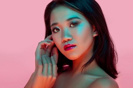High Fashion model woman in colorful bright lights posing in studio, portrait of beautiful sexy girl with trendy make-up. Art design, colorful make up. Over colourful vivid background.の写真素材