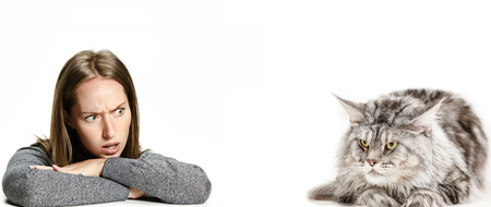 The surprised and indignant woman and her cat over white background at studio. The concept of humans and animals same emotionsの写真素材