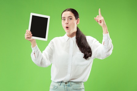 Portrait of a confident casual girl showing blank screen of laptop isolated over green background.