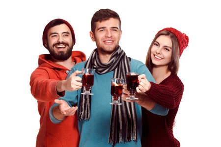 Smiling european men and women during party photoshoot. The guys posing as friends at studio fest with wineglasses with hot mulled wine on foreground.の写真素材