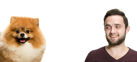 Emotional Portrait of man and his dog, concept of friendship and care of man and animal. The cute Little young pomeranian cob isolated over white studio backgroundの写真素材