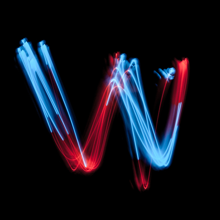 Letter W of the alphabet made from neon sign. The blue light image, long exposure with colored fairy lights, against a black backgroundの写真素材