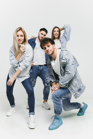 Group of smiling friends in fashionable jeans. The young men and woman posing at studio. The fashion, people, happy, lifestyle, clothes conceptの写真素材