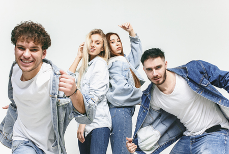Group of smiling friends in fashionable jeans. The young men and woman posing at studio. The fashion, people, happy, lifestyle, clothes conceptの写真素材