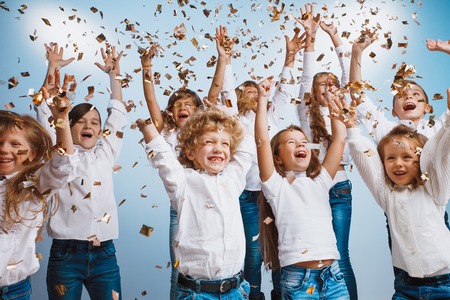 Adorable kids have fun together throw colourful confetti at birthday party. They playing together in...