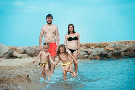 Happy family enjoying walk on the sea beach. The summer, childhood, holiday, leisure, lifestyle, travel, vacation conceptの写真素材