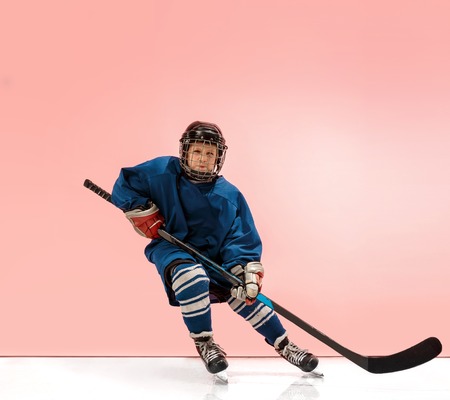 A hockey player in uniform with equipment over pink studio background. The athlete, child, sport, action conceptの写真素材